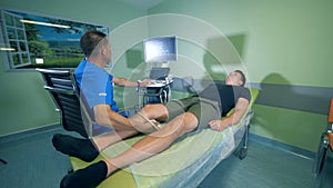 Man lies on a bed while a doctor scans his knee with a ultrasound device.