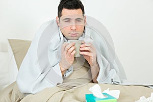 man lies in bed sick with colds and flu