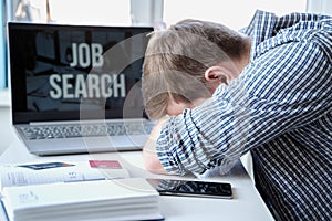 Man lies face down on table next to laptop. Unemployment, crisis, stress, job loss. Looking for remote work at home.Mobile phone,