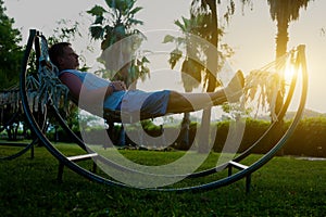 A man lies in a hammock at sunset