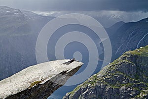 Man lies on Trolltunga rock (Troll\'s Tongue rock) and makes the photo with the Norwegian mountain landscape