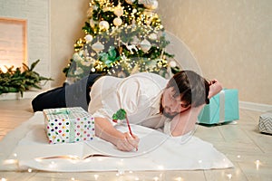 a man lies under the Christmas tree at home and fills out documents.