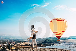 Man lifted up a woman on his hands. Couple in love among balloons. Couple in love in Pamukkale. Couple in Turkey. Honeymoon trip.