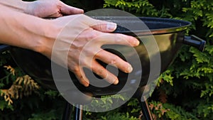 Man lifting BBQ grill outdoors