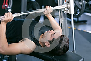 Man lifting dumbbell weights while lying down in gym.