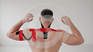 The man lifting his arms, back view. Sportsman having kinesiotherapy after workout.