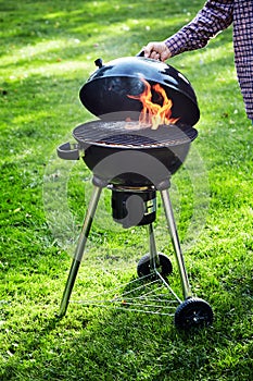 Man lifting the lid of a portable barbecue fire