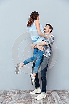 Man lifting up his girlfriend on gray background