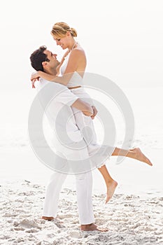 Man lifting woman on the beach