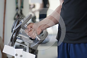 Man lifts dumbbell weight from rack in gym