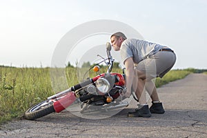 A man lifts a motorcycle that fell after an accident