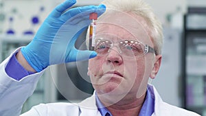 Man lifts the test-tube up at the laboratory