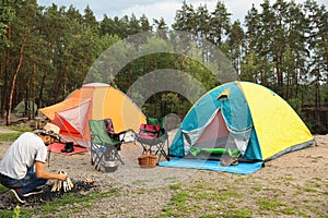 Man lighting bonfire near camping tents