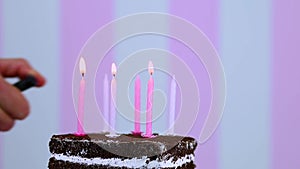 Man lighting candle on chocolate birthday cake.