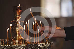 Man lighting candle near stand in church, closeup. Baptism ceremony