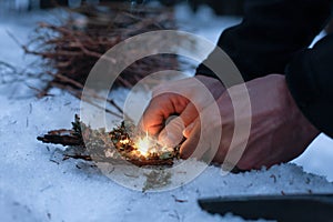 Man lighting a fire in a dark winter forest