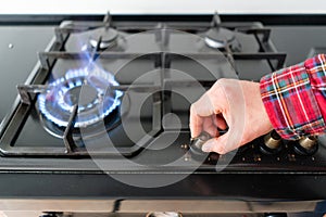 A man lighting the gas-stove with by means of automatic electric ignition. Modern gas burner and hob on a kitchen range