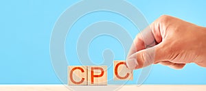 man is lining up wooden blocks in the cpc lettering. cost per click concept.