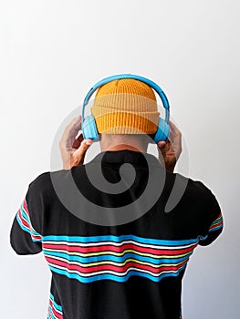 Man listening blue headphones, white background. Back view.