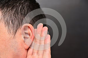 Man is listening intently with holds his hand to his ear