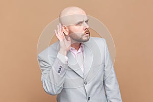 Man listening intently to secret information, private talk, holding hand near ear to hear better.