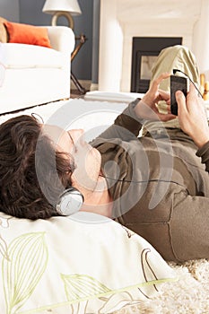 Man Listening To MP3 Player Laying On Rug photo