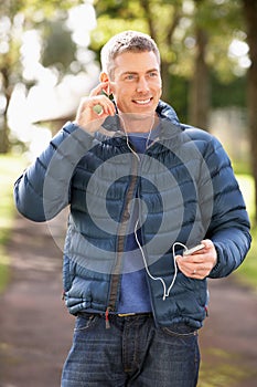 Man Listening To MP3 Whilst Walking In Park photo