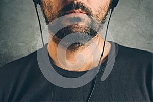 Man listening to music on headphones, half face portrait