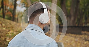 Man listening to music using mobile phone and headphones at park