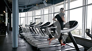 Man listening to music via headphones and running on treadmill