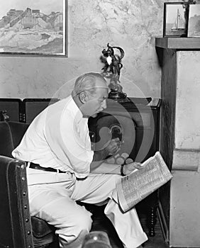 Man listening to radio and reading newspaper photo