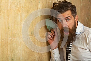 Man listening through the wall with the cup. Secrets and gossip concept. Neighbour and secret. Funny man with beard hear
