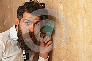 Man listening through the wall with the cup. Secrets and gossip concept. Neighbour and secret. Funny man with beard hear