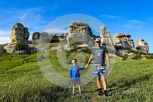 A man and a little boy on the background of a picturesque view of the Bakhchisarai sphinxes. Bakhchisarai. May 2021.