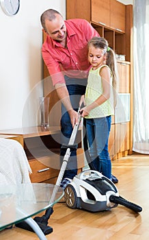 Man and little girl vacuuming at home