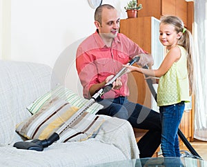 Man and little girl vacuuming at home