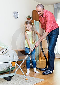 Man and little girl vacuuming at home