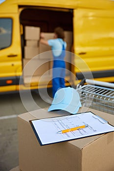 Man loader packing boxes into minivan, focus on delivery checklist