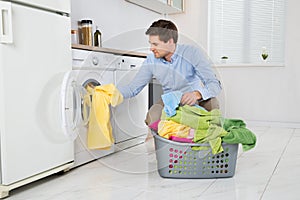 Man Loading Clothes Into Washing Machine