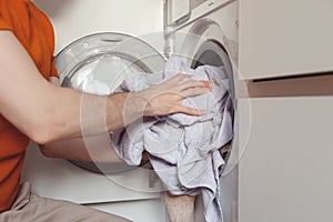 Man loading color clothes and towels into built-in washing machine