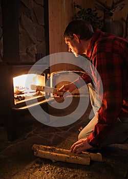 Man loading firewood in stove at night