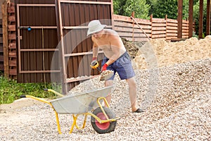 Man loading gravel into wheelbarrow with a shovel