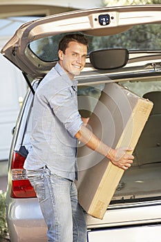 Man Loading Large Package Into Back Of Car