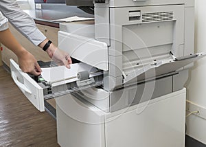 Man loading paper into photocopier`s tray at office