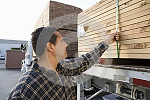 Man Loading Stack Of Plank On Trailer