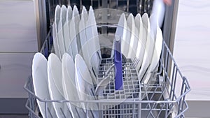 Man loading and unloading dishwasher white dishes, cutlery, high speed video.