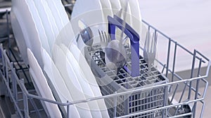 Man loading and unloading dishwasher white dishes, cutlery, high speed video.