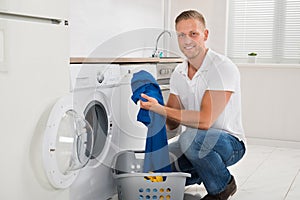 Man Loading Washing Machine With Clothes