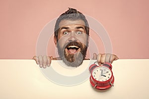 Man with long beard hold alarm clock.