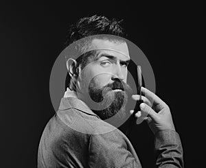 Man with long beard holds blade for razor. Barbershop advertising